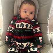 Valentin participe au concours pour gagner de l'argent avec cette photo : baby, child, infant, onesie, holiday_clothing, snowflake_pattern, christmas_theme, chair, cushion, indoor, cute, portrait, seated, young_child, person, face, looking, cozy, warm_clothing, expression