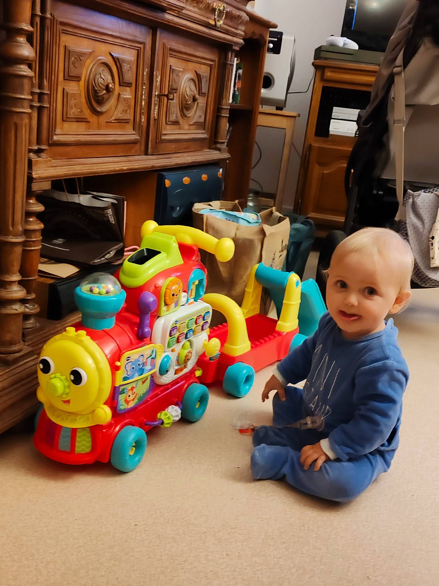 Valentin participe au concours pour gagner de l'argent avec cette photo : baby, baby_toys, cabinetry, drawer, flooring, fun, hardwood, home_appliance, leisure, person, play, riding_toy, room, sitting, smile, television, toddler, toy, toy_vehicle, wheel