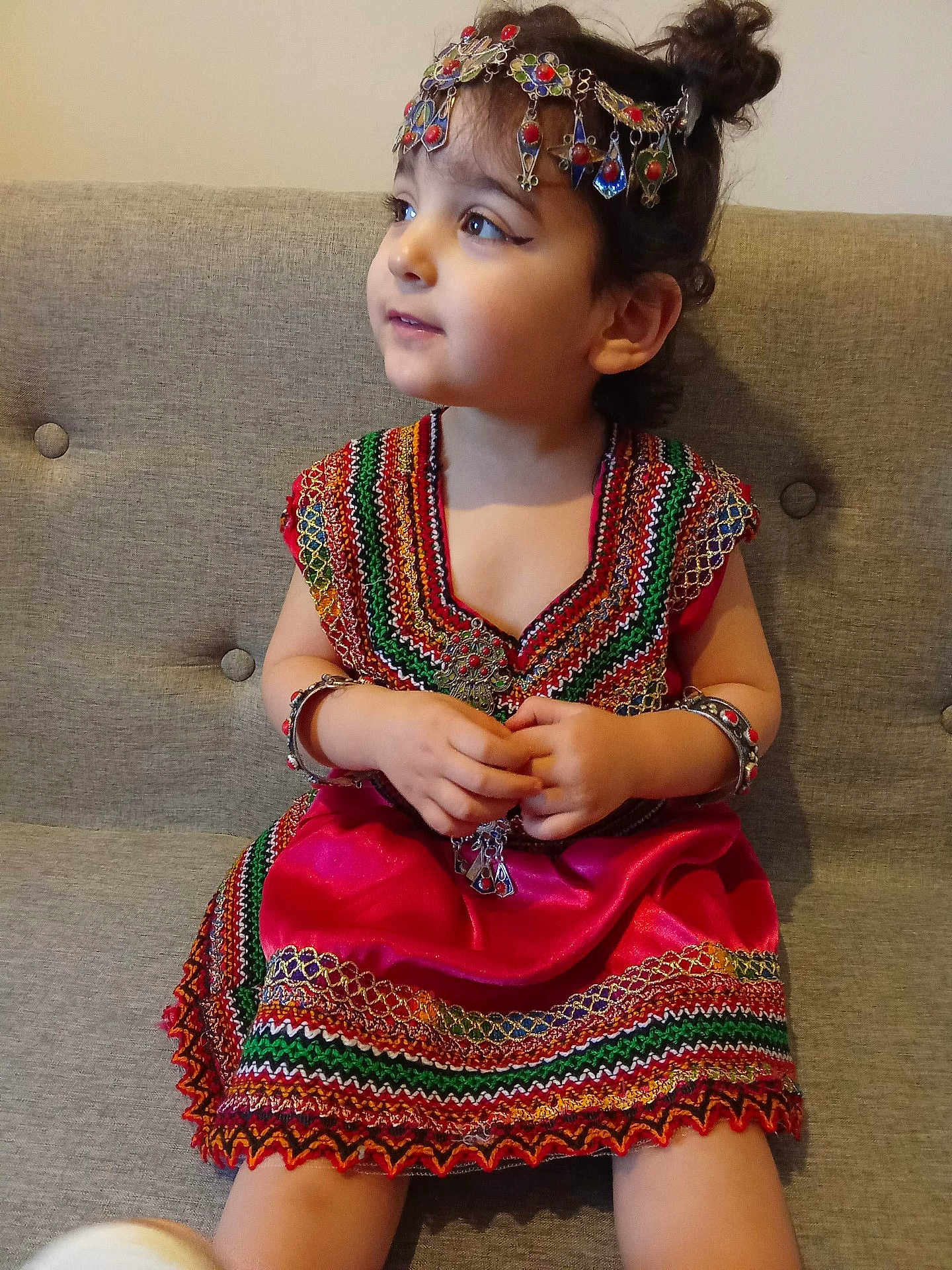 Zira a rejoint le concours — aidez-le/la à gagner de superbes lots ! child, toddler, traditional_clothing, dress, jewelry, bracelets, headpiece, sitting, couch, indoors, portrait, cute, decorative, colorful, patterned, young_child, face, eyes, hands, hair