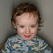 Landon joined the competition — help win amazing prizes! baby, blue_eyes, camouflage, cheeky, child, cozy, curly_hair, cute, expression, face, indoor, light, onesie, person, playful, portrait, smile, toddler, wall, young_child