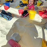 Roselina joined the competition — help win amazing prizes! child, children, sand, sandbox, toys, buckets, shovels, toy_trucks, smiling, curly_hair, play, indoor, yellow_bucket, red_bucket, plastic_toys, happy, playing, casual_clothing, multiracial_children, daylight