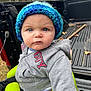 baby, beanie, bonnet, cap, clothing, coat, face, glove, hat, head, hood, jacket, knitwear, pants, person, photography, portrait, sweater, transportation, vehicle