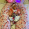 baby, sleeping, cushion, floral_pattern, stuffed_toy, night_light, bunny_light, bear_light, headband, knitted_sweater, blanket, bed, child, indoor, soft_toy, cute, resting, infant, colorful, cozy