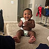 baby, smiling, diaper, tissue, couch, indoor, child, happy, sitting, home, furniture, person, foot, wall, door, chair, floor, clothing, interior, living_room