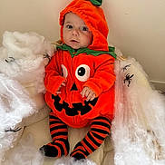 Ezio participe au concours pour gagner de l'argent avec cette photo : baby, pumpkin_costume, halloween, orange, black_stripes, striped_tights, spiders, cobwebs, costume, cute, child, indoor, holiday, festive, sitting, portrait, face, hooded_outfit, soft_texture, seasonal