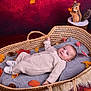 Ezio a rejoint le concours — aidez-le/la à gagner de superbes lots ! baby, basket, blanket, autumn_leaves, pinecones, figurine, squirrel, wooden_stump, knit_outfit, footwear, cozy, portrait, indoor, red_background, soft_texture, child, cute, laying_down, decor, fall_theme