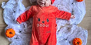 Ezio participe au concours pour gagner de l'argent avec cette photo : baby, infant, halloween, pumpkin, costume, orange_clothing, hat, spider_web, toy_pumpkin, floor, decorations, smiling, cute, festive, holiday, child, person, lying_down, indoor, celebration