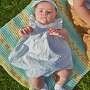 Lilah joined the competition — help win amazing prizes! baby, child, infant, blanket, grass, outdoor, headband, dress, sock, person, blue, knitted_blanket, summer, sunlight, cute, young_child, sitting, natural_light, portrait, casual_clothing