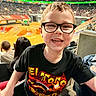 Ashton joined the competition — help win amazing prizes! child, boy, glasses, smile, tshirt, indoor, arena, spectators, event, dirt_track, seating, people, crowd, happy, portrait, casual_clothing, short_hair, fun, leisure, family