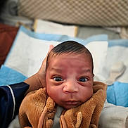Imran a rejoint le concours — aidez-le/la à gagner de superbes lots ! baby, infant, face, eyes, expression, hand, clothing, vest, brown, warm, soft, indoor, portrait, person, newborn, curious, cozy, closeup, head, skin