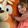 child, girl, plush_toy, stuffed_animal, orange, smile, cute, indoor, dress, toy, happy, face, cuddly, childhood, soft, playful, person, portrait, light, cozy