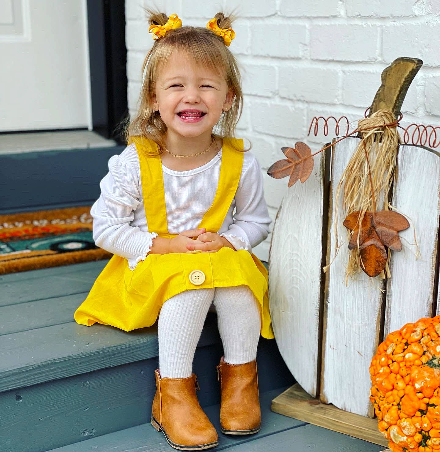 Sophia is registered to the contest to win money with this photo: baby_toddler_clothing, boot, calabaza, child, costume, fun, happy, human_leg, joy, knee, orange, person, room, shoe, sitting, smile, sneakers, sock, thigh, toddler