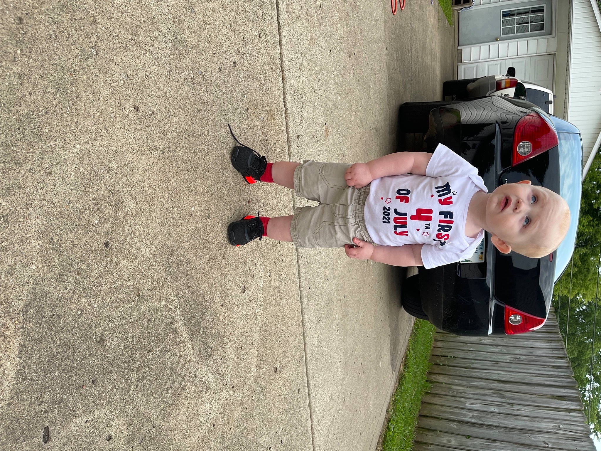 Landon is registered to the contest to win money with this photo: asphalt, carmine, child, composite_material, concrete, footwear, fun, leisure, outdoor_shoe, person, recreation, road_surface, shadow, smile, surprise, toddler, tree, walking_shoe
