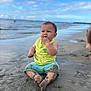 baby, child, sand, beach, water, sky, clouds, wet, sitting, curious, barefoot, summer, outdoor, nature, ocean, shore, muddy, playful, infant, casual_clothing