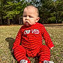 Matteo is registered to the contest to win money with this photo: baby, child, red_onesie, striped_clothing, grass, outdoor, nature, trees, sunlight, shadow, infant, sitting, cute, face, expression, person, park, footwear, daylight, young