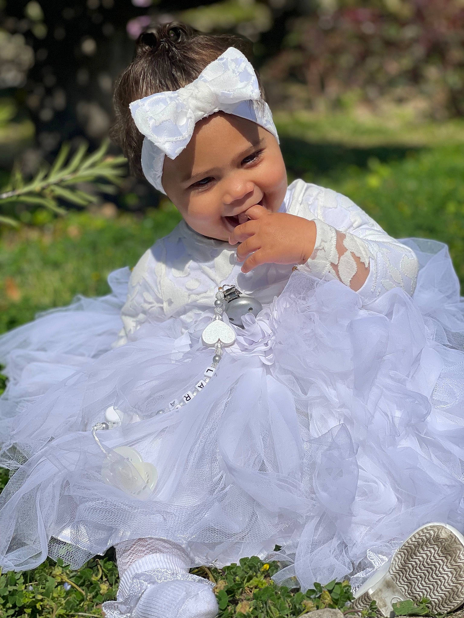 Lara participe au concours pour gagner de l'argent avec cette photo : baby, baby_toddler_clothing, beauty, bridal_accessory, bridal_clothing, dress, embellishment, event, face, flash_photography, grass, happy, headpiece, headwear, human_body, joy, person, pink, plant, sleeve