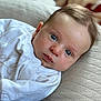 baby, infant, face, blue_eyes, white_clothing, cushion, quilted, close_up, portrait, newborn, soft_light, skin, head, cute, laying_down, indoors, young_child, expression, person, baby_boy