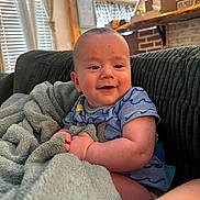 Alden-Paul is registered to the contest to win money with this photo: baby, blanket, couch, child, smile, happy, indoor, face, infant, person, cozy, furniture, home, soft, comfort, clothing, cute, portrait, relaxing, natural_light