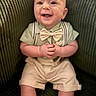 Alden-Paul is registered to the contest to win money with this photo: baby, child, smile, bow_tie, suspenders, green_chair, seated, happy, cute, infant, portrait, clothing, shorts, shirt, indoors, furniture, person, face, hands, legs