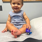 Kashton joined the competition — help win amazing prizes! baby, child, curly_hair, cute, duck_toy, flashlight, foot, happy, indoor, infant, light_switch, medical_table, person, romper, sitting, skin, smiling, striped_clothing, toy, wooden_frame