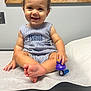 baby, child, curly_hair, cute, duck_toy, flashlight, foot, happy, indoor, infant, light_switch, medical_table, person, romper, sitting, skin, smiling, striped_clothing, toy, wooden_frame
