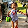 Kashton is registered to the contest to win money with this photo: toddler, child, smiling, curly_hair, toy, slippers, bubbles, outdoor, porch, sunlight, playful, happy, running, summer, casual_clothing, person, green, blue, red, background