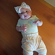 Maryjane joined the competition — help win amazing prizes! baby, infant, headband, bow, clothing, pastel_colors, floral_pattern, wooden_surface, cute, child, portrait, lying_down, soft_lighting, indoors, person, small_hands, baby_pants, baby_shirt, expression, adorable