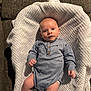 Greyson joined the competition — help win amazing prizes! baby, infant, onesie, blanket, couch, blue_clothing, face, hands, legs, socks, indoor, curious, lying_down, soft_texture, wood_floor, comfortable, young_child, portrait, casual, cozy