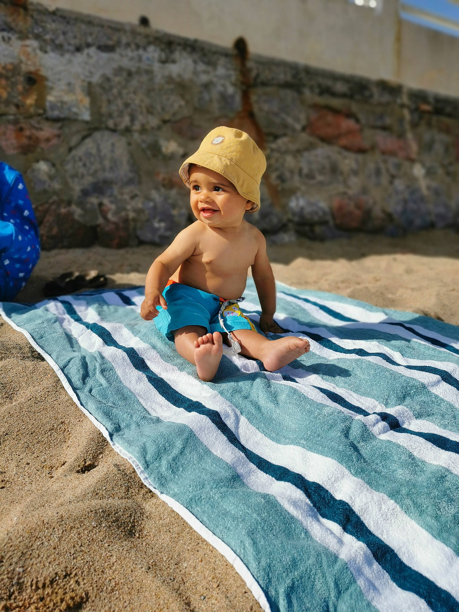 Kingsley participe au concours pour gagner de l'argent avec cette photo : baby, blue, body_of_water, cap, child, event, fashion_accessory, fun, happy, hat, headwear, landscape, leisure, linens, person, play, recreation, rock, sand, sitting