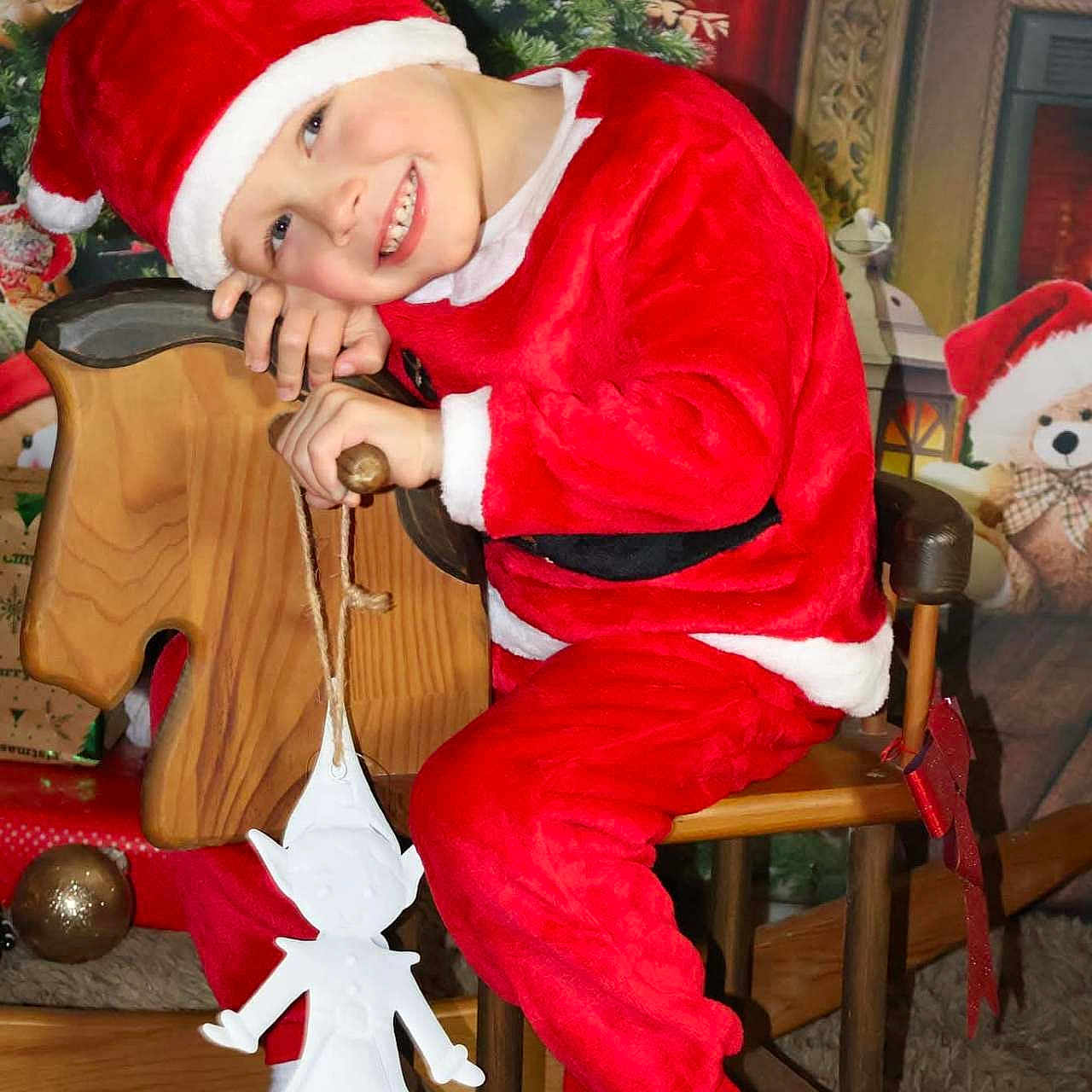 Coppin participe au concours pour gagner de l'argent avec cette photo : child, christmas_costume, christmas_tree, decoration, festive, gift_wrap, happy, holiday_decor, holiday_season, indoor, portrait, red_clothing, rocking_horse, santa_hat, smiling, stocking, teddy_bear, toy, white_socks, wooden