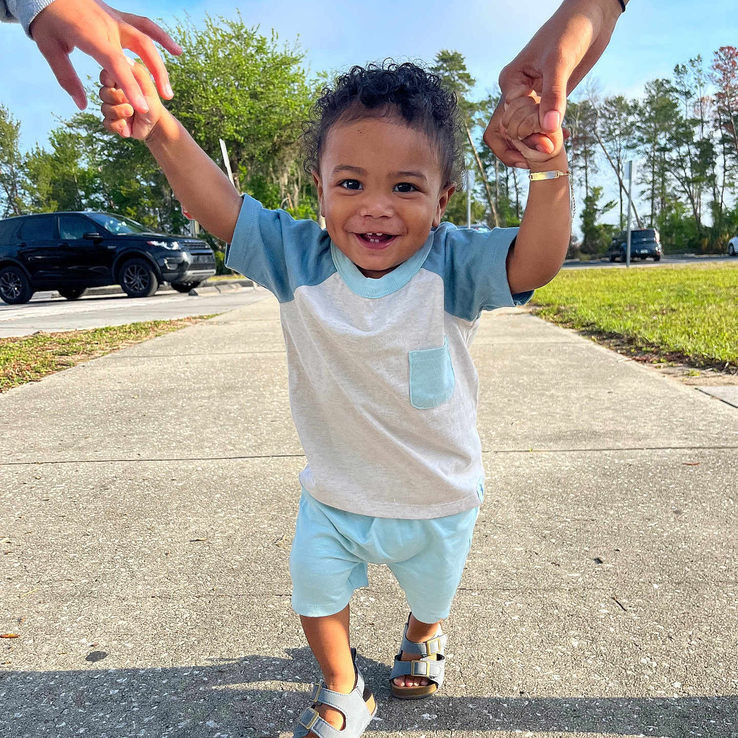Jeury is registered to the contest to win money with this photo: blue_sky, car, casual, child, clothing, curly_hair, daytime, family, grass, happy, holding_hands, outdoor, person, sandals, sidewalk, smiling, sunny, toddler, trees, walking