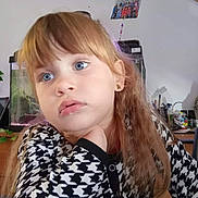 Elina a rejoint le concours — aidez-le/la à gagner de superbes lots ! blue_eyes, casual, child, earrings, face, fish_tank, furniture, girl, hand_on_chin, home, indoor, light, long_hair, patterned_sweater, photo_on_wall, plant, portrait, table, thoughtful, young