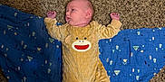 Colin joined the competition — help win amazing prizes! baby, infant, onesie, yellow_clothing, blanket, blue_blanket, carpet, floor, lying_down, sleepy, face, person, child, indoor, pajamas, pattern, soft_texture, cute, resting, baby_clothing