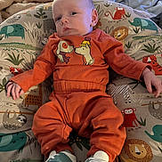 Colin joined the competition — help win amazing prizes! baby, infant, child, orange_clothing, sneakers, animal_print, cushion, blanket, indoor, cute, portrait, resting, comfort, soft_toys, patterned_fabric, small_hands, small_feet, face, person, relaxing