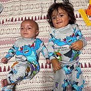 Leonardo is registered to the contest to win money with this photo: baby, toddler, siblings, children, portrait, smiling, lying_down, blanket, bedroom, pajamas, matching_outfits, monster_print, cartoon, patterned_fabric, infant, young_child, faces, indoor, family, photography
