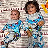 baby, toddler, siblings, children, portrait, smiling, lying_down, blanket, bedroom, pajamas, matching_outfits, monster_print, cartoon, patterned_fabric, infant, young_child, faces, indoor, family, photography