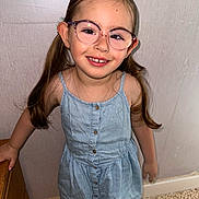 Louna a rejoint le concours — aidez-le/la à gagner de superbes lots ! child, girl, smiling, glasses, pigtails, dress, indoor, wall, furniture, happy, portrait, standing, person, casual, young, cute, hair, fashion, accessory, light