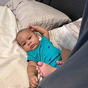 Xane is registered to the contest to win money with this photo: baby, infant, bed, pillow, blanket, blue_clothing, foot, hand, face, cute, indoor, person, child, sleepwear, head, lying_down, skin, expression, relaxing, toddler