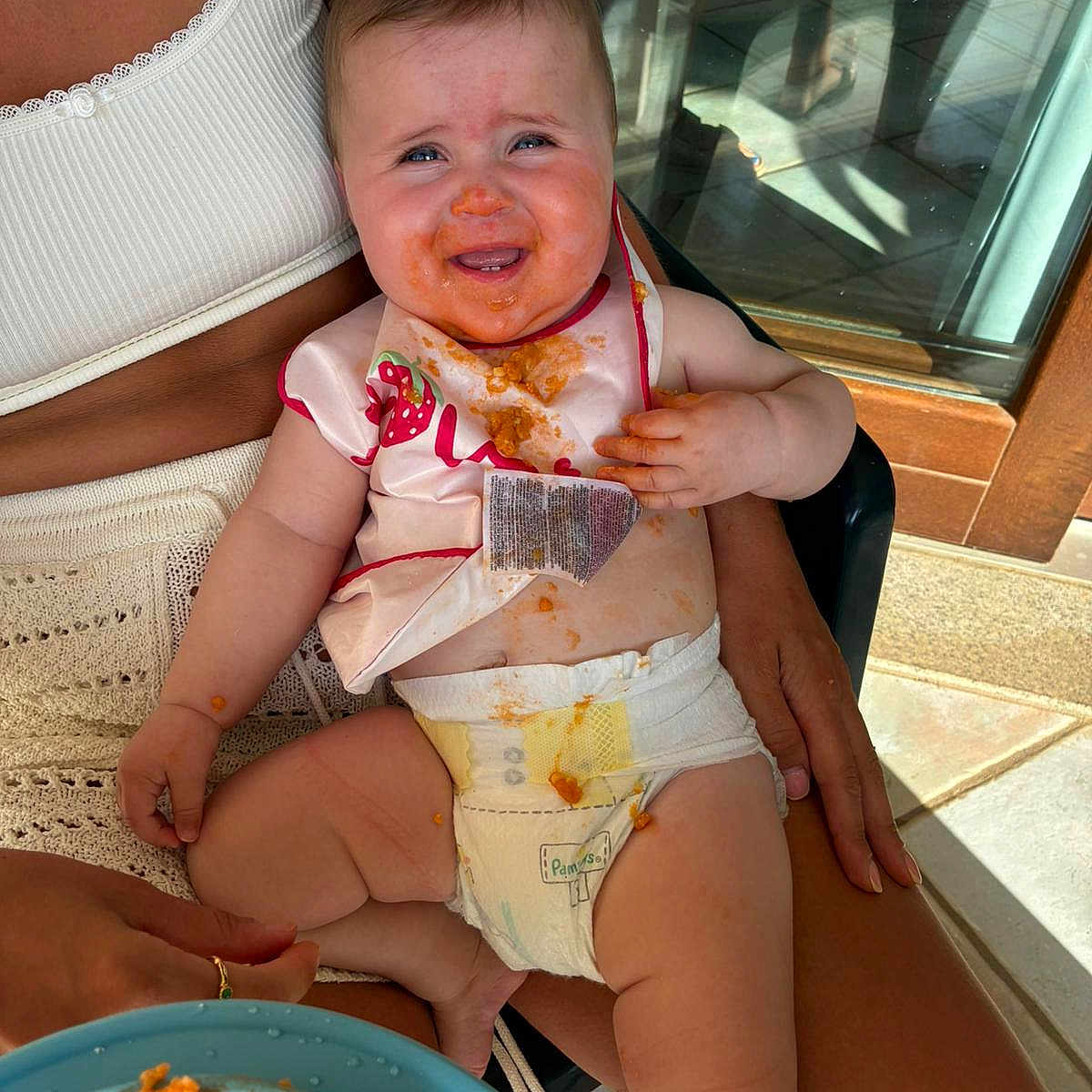 Willow is registered to the contest to win money with this photo: adult, baby, bib, child, clothing, diaper, expression, feeding, food, food_on_face, indoor, lap, messy, person, plate, sitting, skin, spaghetti, sunlight, table