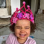 child, toddler, smile, crown, pink_crown, curly_hair, teeth, pajamas, indoor, marble_floor, drawing_paper, chair, backpack, happy, portrait, closeup, home_interior, playtime, cozy, cute