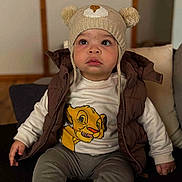 Owen a rejoint le concours — aidez-le/la à gagner de superbes lots ! cartoon_print, child, couch, cute, expression, eyes, face, hat, indoor, knit_hat, lion_print, pants, pom_poms, portrait, sitting, socks, toddler, vest, white_sweater, young_child