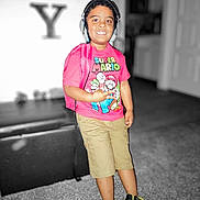 Elijah is registered to the contest to win money with this photo: child, boy, headphones, backpack, super_mario, tshirt, shorts, sneakers, indoor, carpet, furniture, blurred_background, smiling, standing, person, casual_clothing, young, playful, portrait, colorful