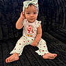baby, child, infant, pajamas, headband, strawberry, cute, sitting, black_couch, plush, indoor, clothing, smile, face, person, foot, hand, window, curious, comfortable