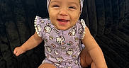 Janali is registered to the contest to win money with this photo: baby, child, smiling, purple_clothing, headband, cute, sitting, happy, indoor, plush_surface, infant, portrait, one_person, face, toes, arm, leg, playful, young_child, casual