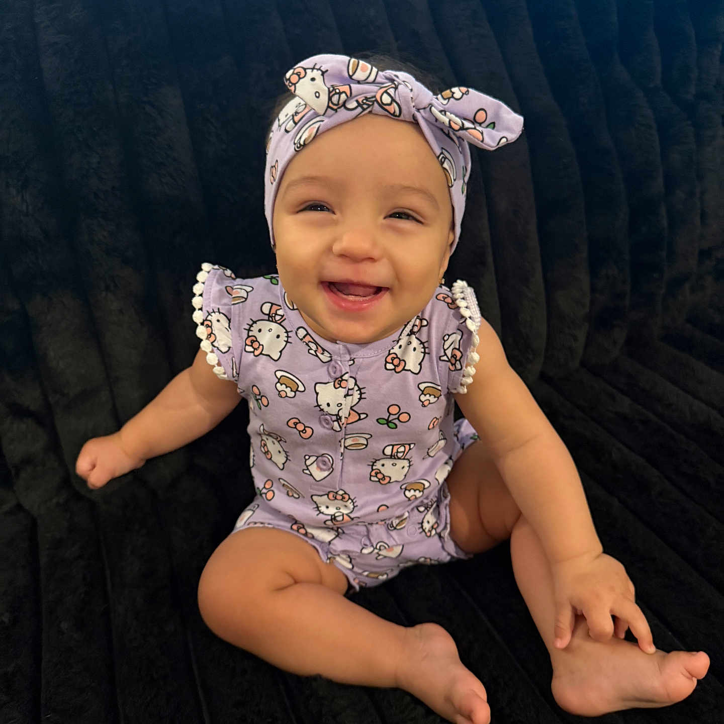 Janali is registered to the contest to win money with this photo: baby, child, smiling, purple_clothing, headband, cute, sitting, happy, indoor, plush_surface, infant, portrait, one_person, face, toes, arm, leg, playful, young_child, casual