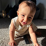 Janali is registered to the contest to win money with this photo: baby, child, crawling, carpet, remote_control, smiling, sunlight, indoor, person, infant, cute, playful, happy, young_child, face, arm, hand, clothing, floor, shadow
