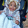 baby, smiling, car_seat, blanket, pacifier, hoodie, child, cute, outdoor, happy, infant, seatbelt, clothing, person, face, sitting, warm, fur, headwear, cozy