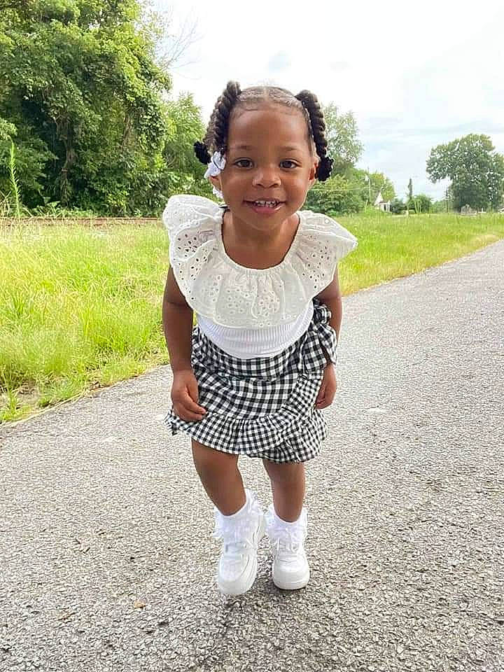 Ashlynn is registered to the contest to win money with this photo: asphalt, baby_toddler_clothing, face, gesture, grass, hair, happy, joy, leaf, neck, pattern, people_in_nature, person, plant, road_surface, sky, sleeve, smile, sock, t_shirt