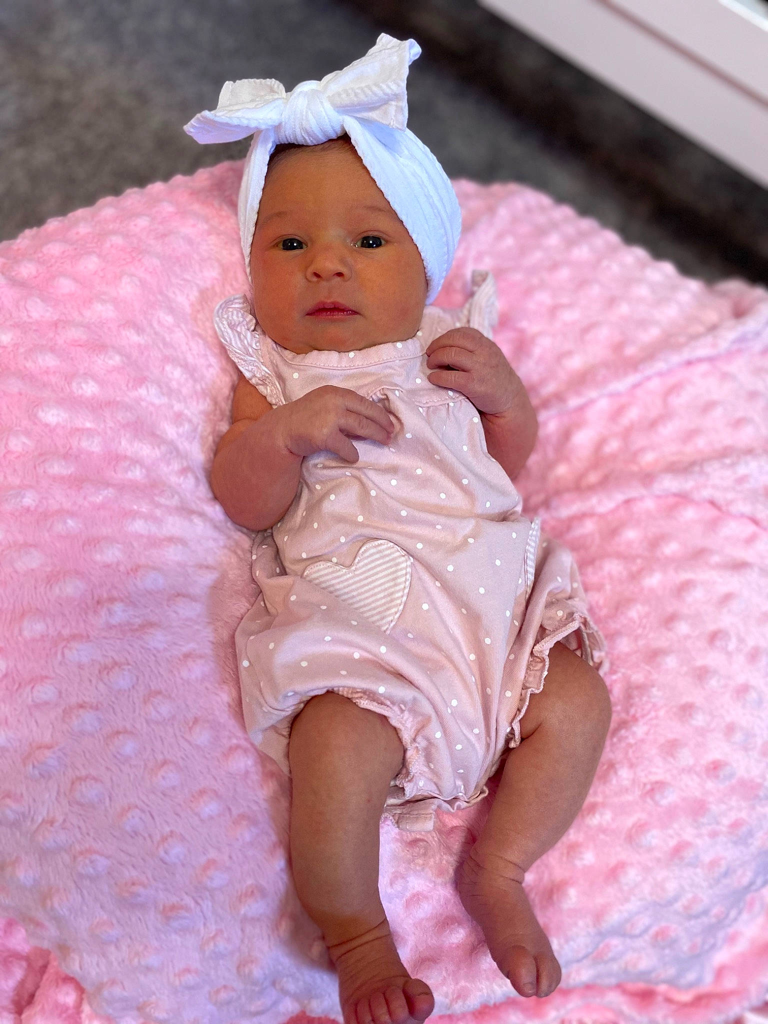 Parker is registered to the contest to win money with this photo: baby, baby_toddler_clothing, cap, cheek, comfort, dress, embellishment, face, happy, headwear, linens, magenta, pattern, peach, person, pink, purple, sitting, skin, sleeve