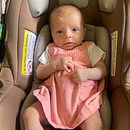 Cali is registered to the contest to win money with this photo: baby, infant, car_seat, pink_dress, white_shoes, socks, child, cute, seated, indoors, looking_at_camera, soft_lighting, car_seat_padding, baby_clothing, small_hands, head_support, baby_face, footwear, baby_girl, comfort